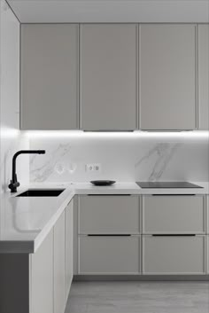 a white kitchen with marble counter tops and stainless steel sink faucets in the center