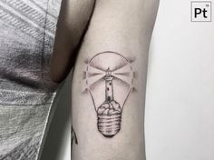 a lighthouse in a light bulb tattoo on the arm