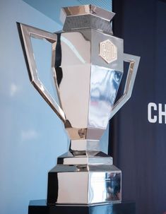 a silver trophy sitting on top of a black table next to a blue wall with the words chase written on it