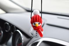 a knitted owl ornament hanging from a car dash board in a vehicle