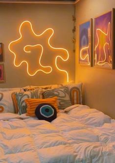 a bed with white comforter and pillows in front of a neon sign on the wall