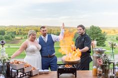 a man and woman standing in front of a fire pit