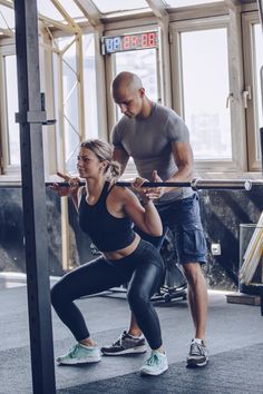 a man and woman doing squats in a gym