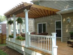 an outdoor deck with white railings and wooden posts, covered in potted plants