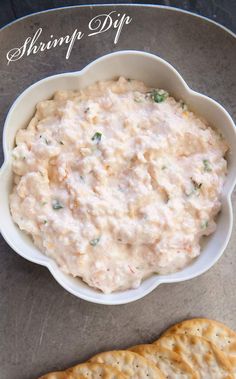 a white bowl filled with dip next to crackers on top of a gray surface