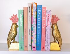 a gold bird figurine sitting on top of a book shelf filled with books