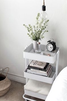 a white shelf with books and a clock on it next to a bed in a room