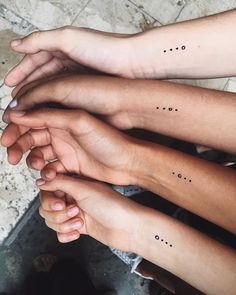 four people are holding their hands together with small dots on them