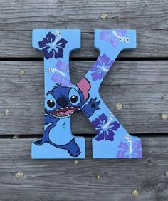 the letter k is painted in blue and purple flowers with lilies on it's face