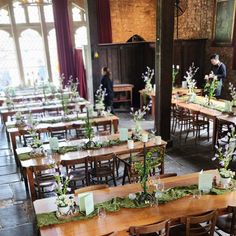 tables and chairs are set up in the dining hall for an event with greenery on them