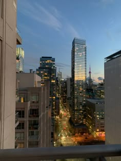 the city skyline is lit up at night with skyscrapers in the foreground and cars on the street below