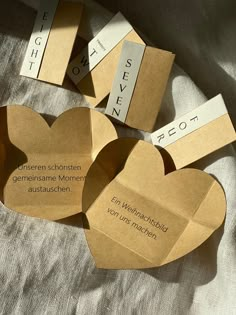 four heart shaped boxes with names on them sitting on a white cloth covered tablecloth