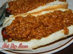 two chili dogs sitting on top of a white plate