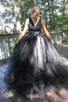 a woman in a black dress standing on a deck