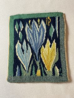 a close up of a rug on a white surface with blue, yellow and green flowers