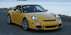 a yellow sports car parked next to the ocean