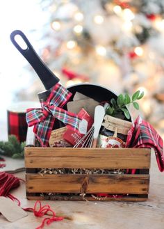 a wooden box filled with food and utensils on top of a table next to a christmas tree