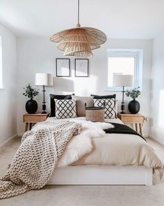 a bed with pillows and blankets on top of it in a bedroom next to a window