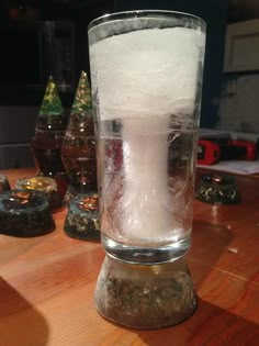 a glass filled with ice sitting on top of a wooden table