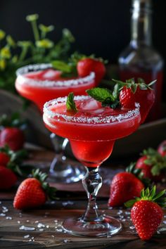 two glasses filled with strawberry margaritas sitting on top of a table next to strawberries