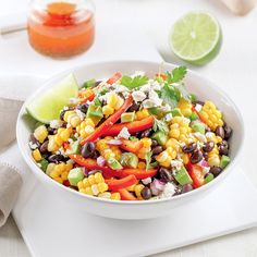 a white bowl filled with corn, black beans and cilantro on top of a table