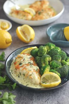 a plate with broccoli, lemons and chicken on it next to other dishes