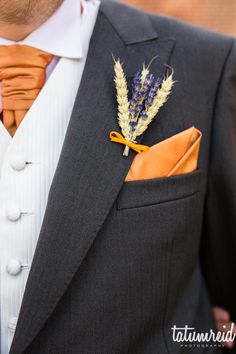 a man in a suit with an orange tie and flower boutonniere on his lapel