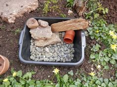 a garden with rocks and stones in a small container on the ground next to plants