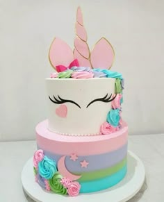 a multi - layered cake decorated with flowers and a unicorn's face on top