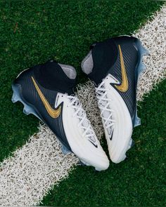 a pair of nike shoes sitting on top of a green grass covered field next to a white line