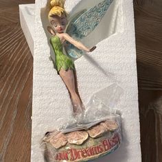 a tinker fairy figurine sitting on top of a piece of paper next to a bag of cookies