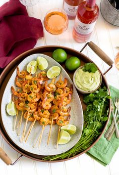 shrimp skewers on a plate with limes and cilantro