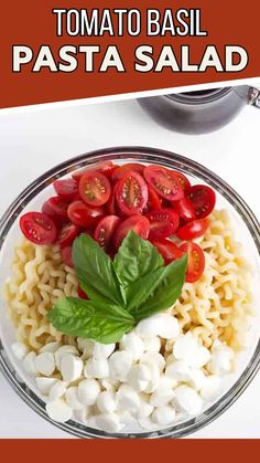 pasta salad with tomatoes, mozzarella and basil in a glass bowl on a white table