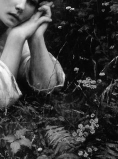 a black and white photo of a woman with her hands on her face in the grass