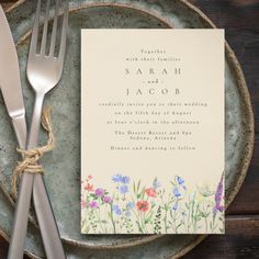 the wedding stationery is laid out on a plate with silverware next to it