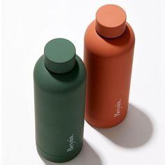 two green and orange bottles sitting next to each other on a white surface with shadows