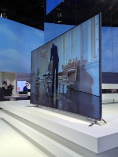 a large flat screen tv sitting on top of a white platform in front of stairs