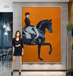 a woman standing in front of a large painting with a horse on it's back