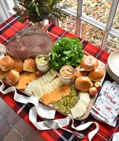 an assortment of cheeses, meats and vegetables on a table with a red checkered tablecloth