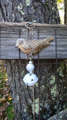 a bird is perched on a fence post with a glass ornament hanging from it's side