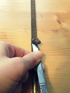 a person holding a pair of scissors on top of a piece of wood next to a knife