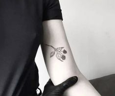 a person with a tattoo on their arm holding a black glove and some berries in it