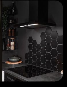 a black kitchen with hexagonal tiles on the backsplash and counter tops