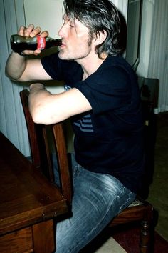 a man sitting at a table drinking from a bottle