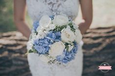 a bride holding a bouquet of white and blue flowers