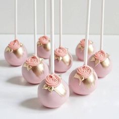 some lollipops with pink frosting and roses on them are sitting in front of each other