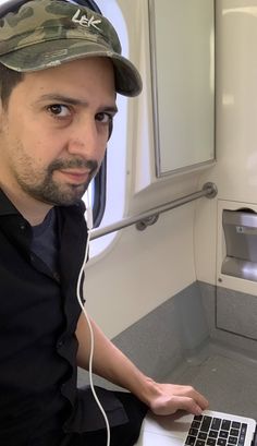 a man sitting in front of a laptop computer on top of a counter next to a sink