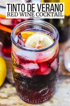 two glasses filled with liquid sitting on top of a table next to lemons and bottles