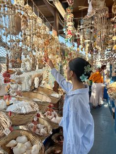 a woman standing in front of baskets filled with shells and seashells at an outdoor market