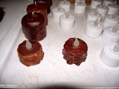 several candles are lined up on a table next to rolls of toilet paper and cups